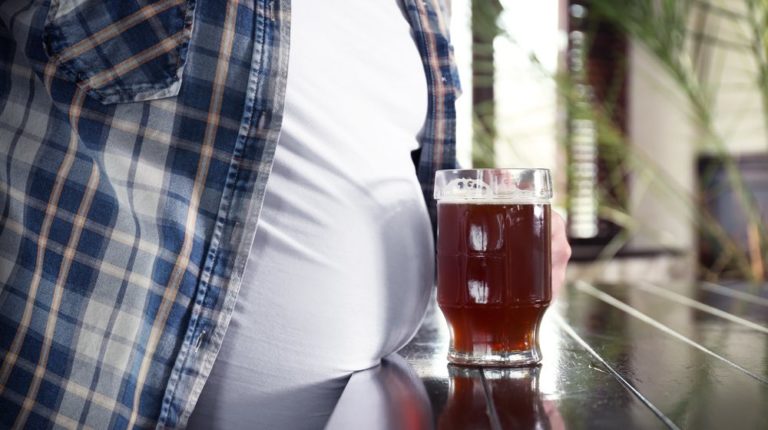 man-holding-glass-beer-near-his | How To Reduce or Eliminate Bloating Effectively | featured
