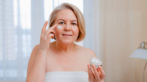 smiling senior woman applying antiaging lotion | Best Retinol Eye Cream Brands