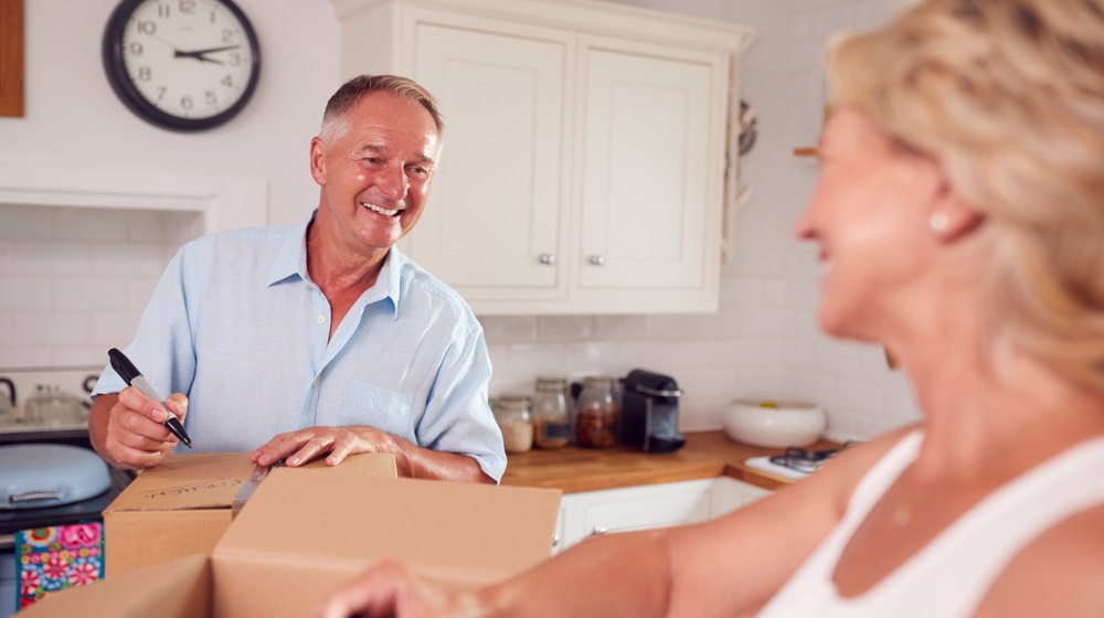 Senior Couple Downsizing In Retirement Packing And Labelling Boxes Ready For Move Into New Home | downsizing your home