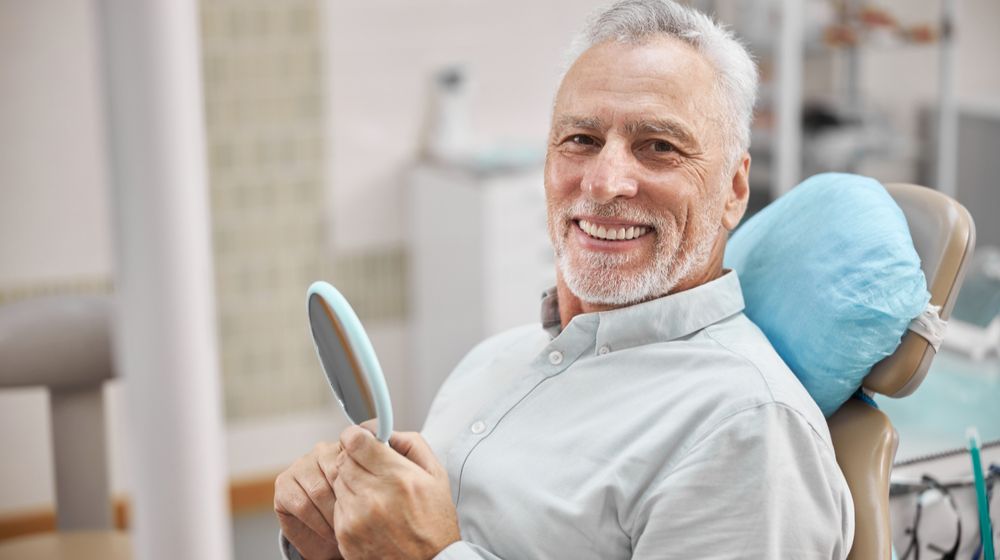 cheerful-patient-sitting-dental-chair-holding probiotics for a great dental health |Featured