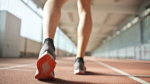 fit runner standing on racetrack in athletics arena | What Is A 6-Minute Mile & How To Do It | Featured