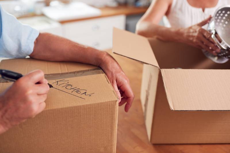 Close Up Of Senior Couple Downsizing In Retirement Boxes Ready For Move Into New Home | Benefits and Advantages of Home Downsizing