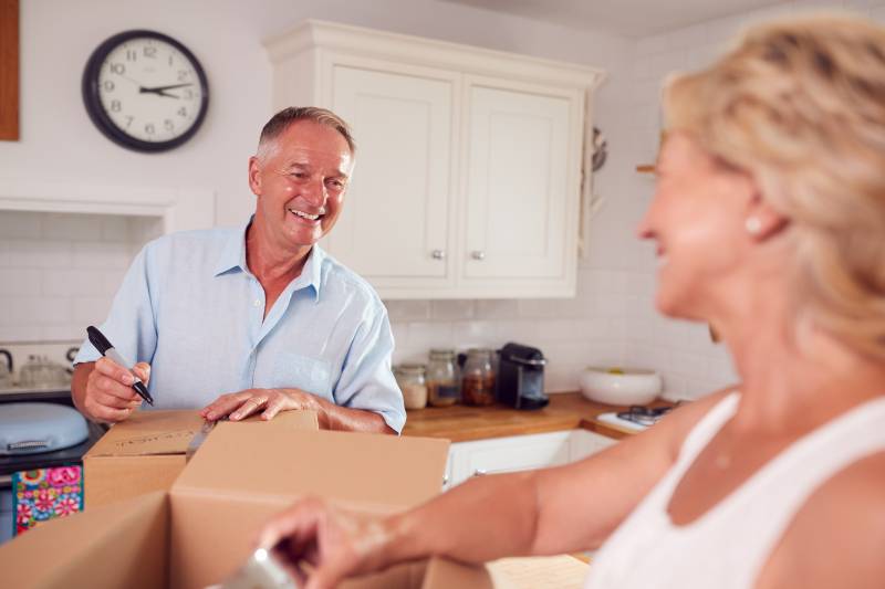 Senior Couple Downsizing In Retirement Packing And Labelling Boxes Ready For Move Into New Home | 4-Step AVID Home Downsizing System