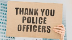 Thank you police officers on a banner in men's hand with blurred background-ss-featured