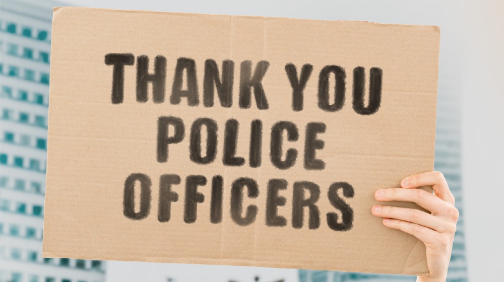 Thank you police officers on a banner in men's hand with blurred background-ss-featured