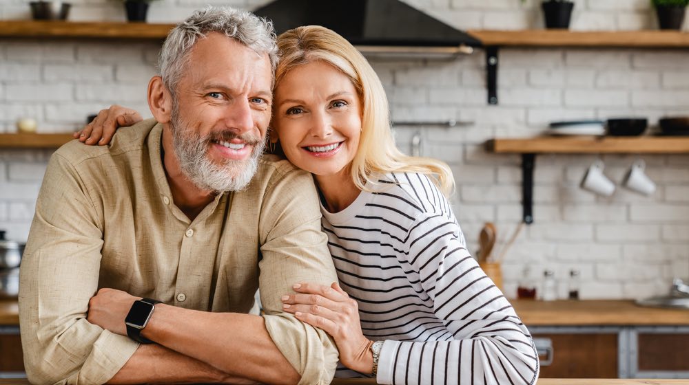 Portrait of middle aged couple hugging while standing together in kitchen at home | Tips for Preventing Alzheimer's Disease |Featured
