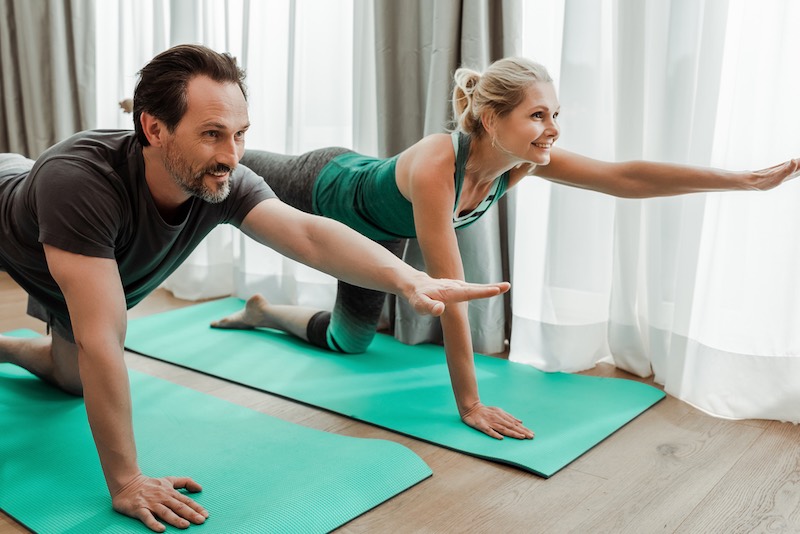 Smiling mature couple exercising on fitness mats in living room | alzheimer's disease symptoms