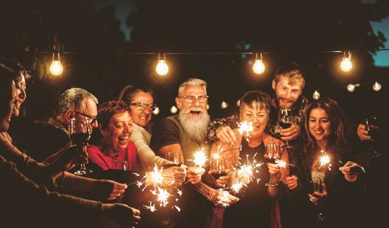 Happy family celebrating with sparklers fireworks at night party - Group of people | Your Retirement Years