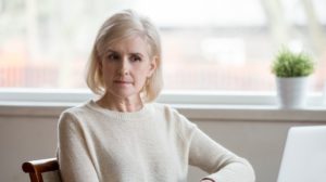 Mature grey haired depressed woman in casual cloth sitting alone at table at home opposite computer thinking about problem difficulties that has arisen | The 10 Main Health Issues of Retirees | Featured