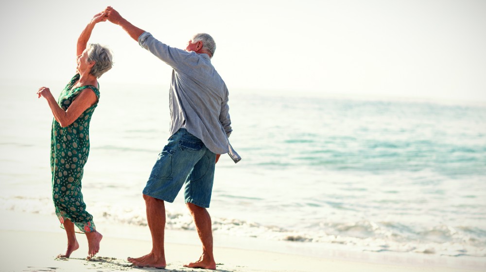 Senior couple dancing at beach on sunny day | Your Retirement Years | featured
