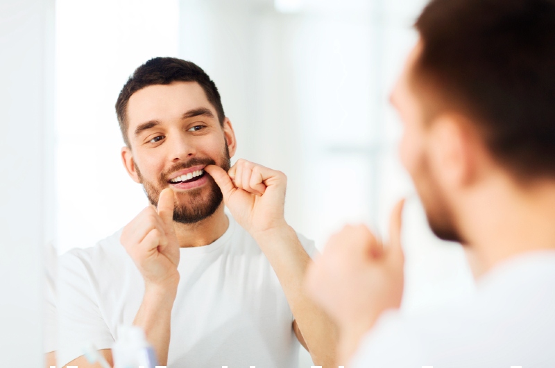 man dental floss cleaning teeth bathroom | Sensitive teeth toothpaste