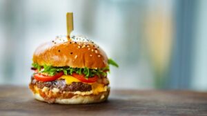 photo of juicy burger on wooden surface | Foods to Avoid After 50 | Featured