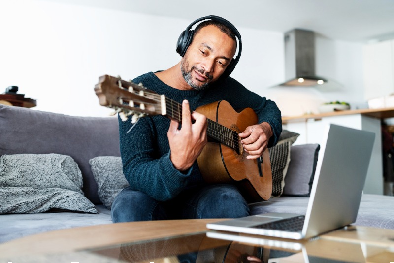 relaxed man playing guitar home using | happy retirement images