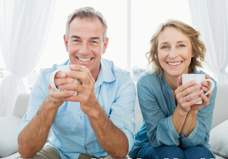 smiling middle aged couple sitting on | california master plan on aging