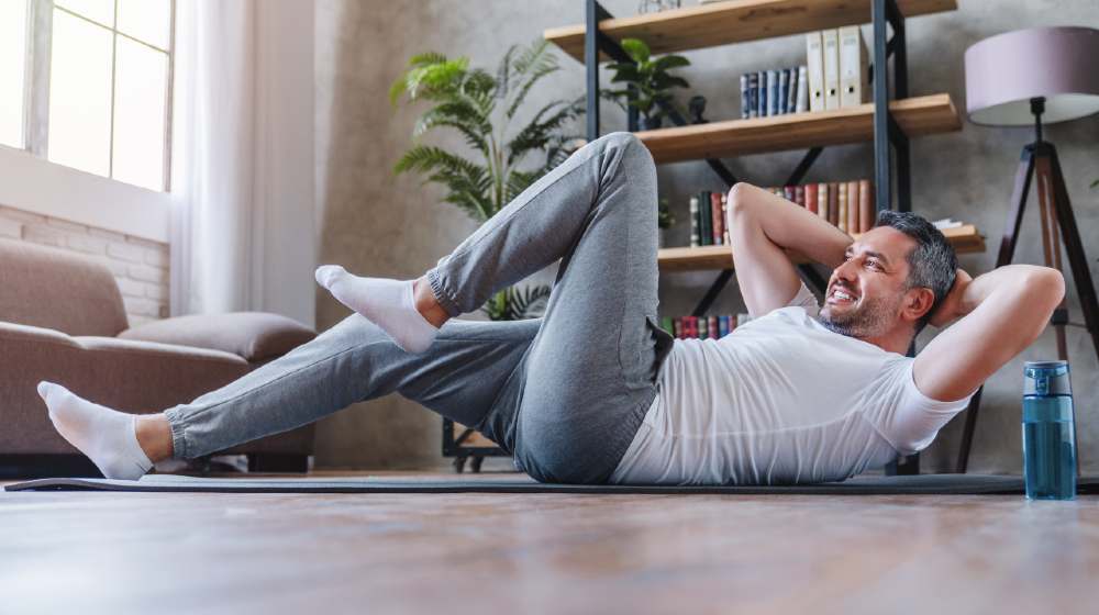 Healthy lifestyle concept. Adult man making abdominal exercises at home | Health Tips For Men Approaching Their 50's | featured