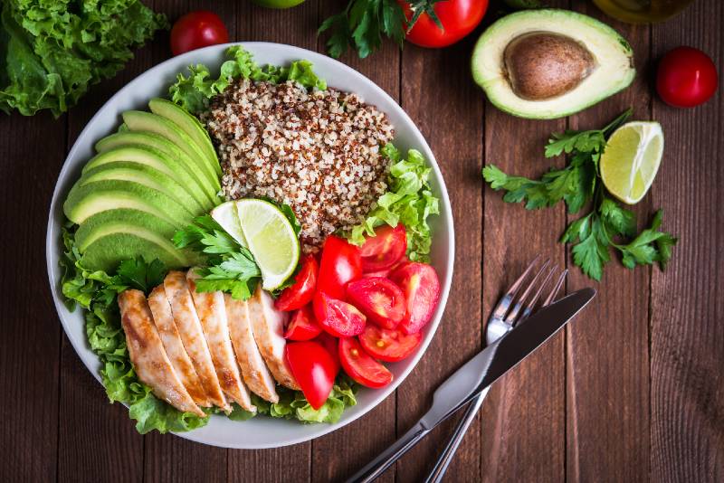 Healthy salad bowl with quinoa, tomatoes, chicken, avocado, lime and mixed greens, lettuce, parsley-Reduce Tummy Fat