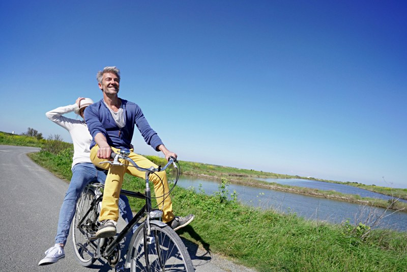 cheerful couple riding bike on sunny | exercise routine for men over 50