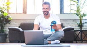 handsome adult man using laptop drinking | Featured