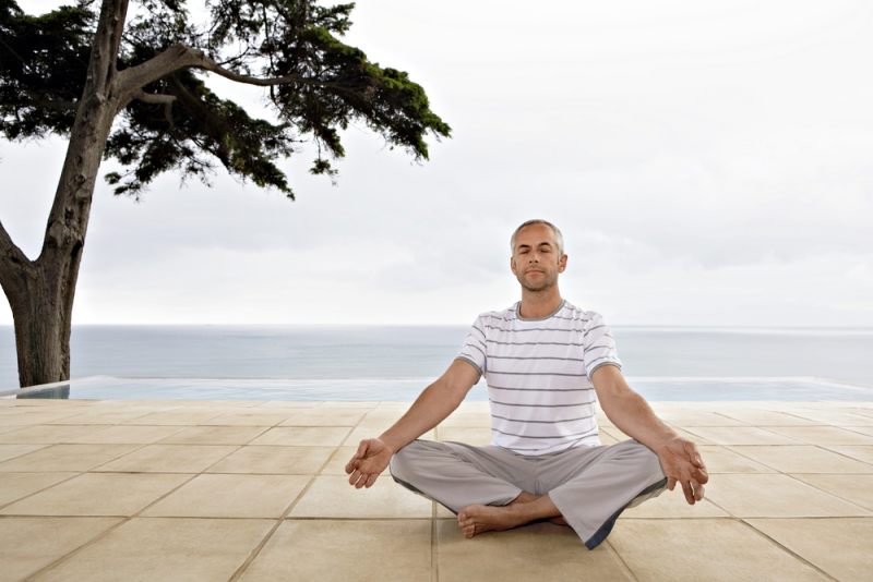 man sitting yoga position on terrace | stretching for golfers
