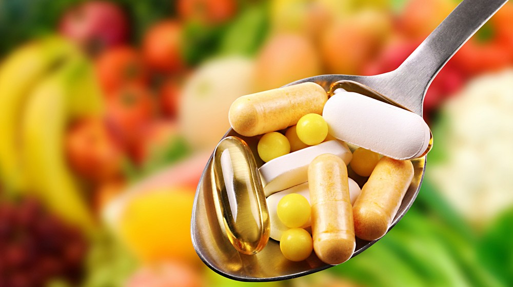 spoon dietary supplements on fruits background | Best Vitamins for Men in Over 40 | Featured