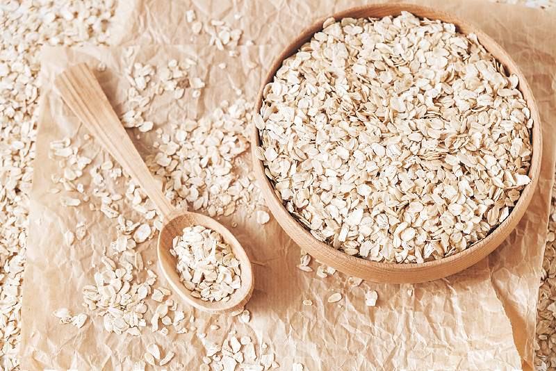 uncooked oatmeal wooden bowl spoon on | foods that lower blood pressure and cholesterol