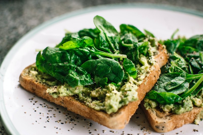 basil leaves on avocado on sliced bread on white ceramic plate | list of foods that lower blood pressure