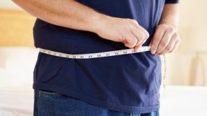 close overweight man measuring waist | Effective Ways to Lose Fat | Featured