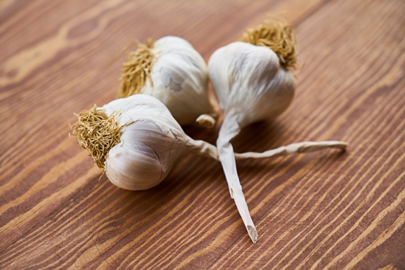 close up photo of three garlic on wooden surface | list of foods that lower blood pressure immediately