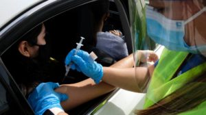 A medical staff gives a drive-thru attendee an influenza vaccine during a drive-thru free flu shots | Biden Calls On States To Offer COVID-19 Vaccine Incentives | featured