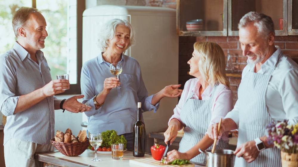 Cheerful aged friends cooking dinner together | Baby Boomers: Should You Downsize? | featured