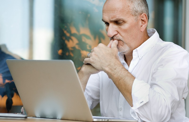looking attentively at a laptop screen reading a legal document sitting at a table-Improve Your Memory