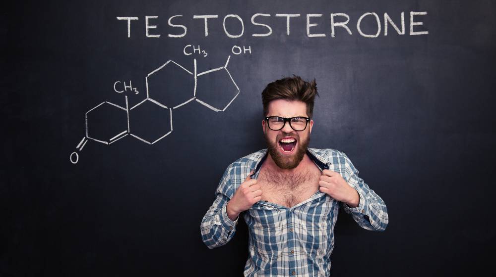 Aggressive young man in glasses screaming and tearing off his shirt over blackboard background | 5 Proven Ways to Boost Your Testosterone Levels Naturally | featured