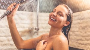 Beautiful naked young woman smiling while taking shower | Cold shower vs hot shower | Featured