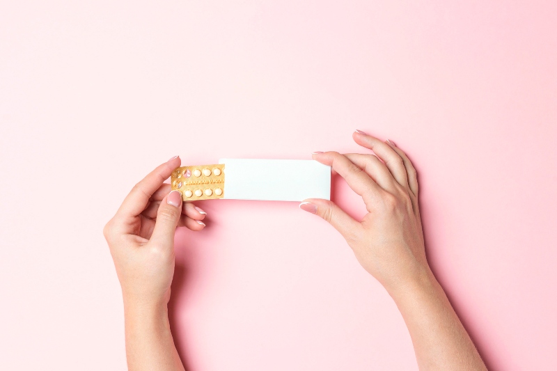 Female Hands Holding Birth Control Pills on Pink Background | How to Fix Hormonal Imbalance