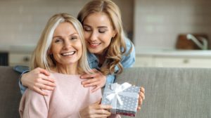 Loving Young Adult Daughter Makes an Unexpected Surprise to Her Mature Attractive Mom | Senior Gift | Featured