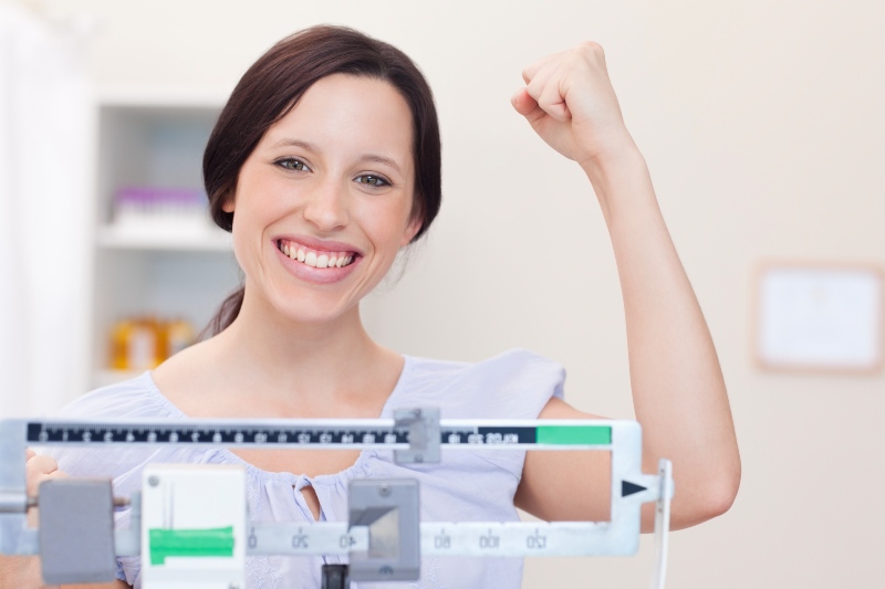 Smiling Young Woman Happy about What the Scale Shows | What Does DASH Diet Mean