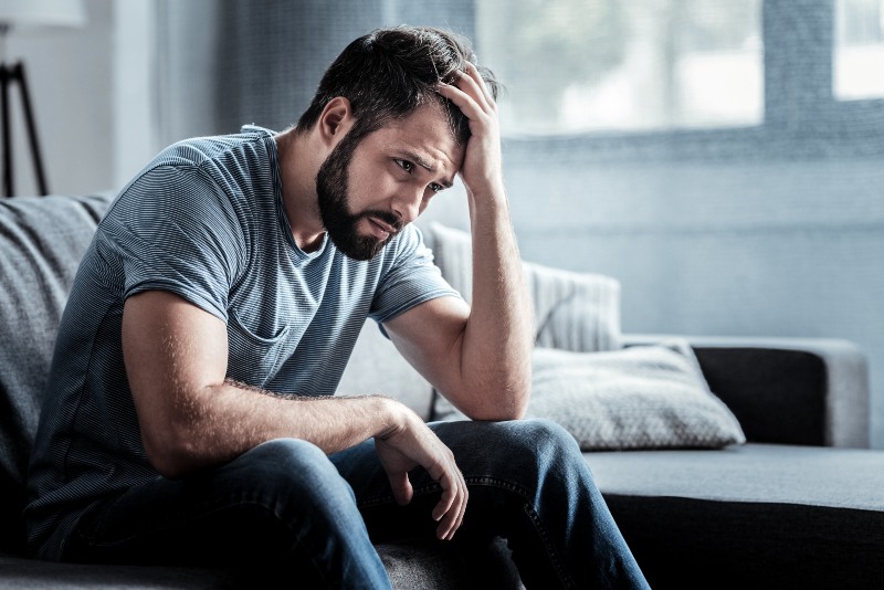 Unhappy Man Sitting on Sofa | Low Iodine Symptoms