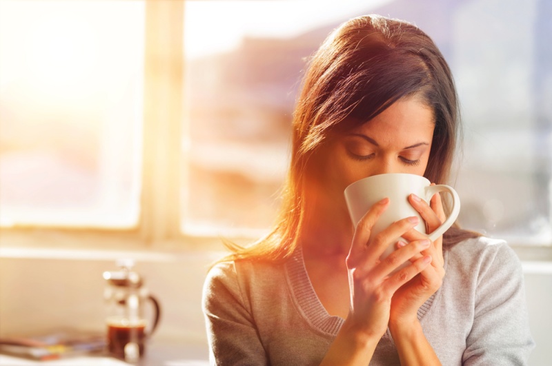 woman drinking coffee home sunrise streaming | pros and cons of drinking coffee