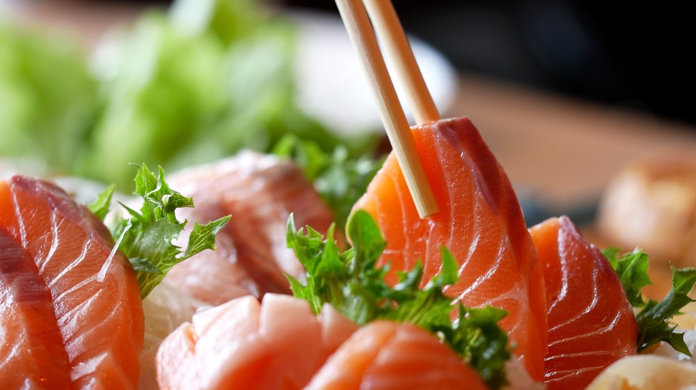 Asian people eating sashimi set in Asian restaurant. Hirame sashimi,salmon sashimi and tuna sashimi dish. Japanese food concept _ Salmon vs Tuna | featured-ss