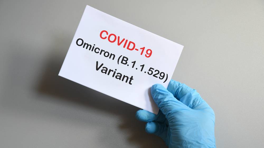 Doctor's hand in blue glove with white paper and text Covid-19 Omicron Variant | South African Doctor Says Don’t Panic On Covid-19 Omicron Variant Yet | featured