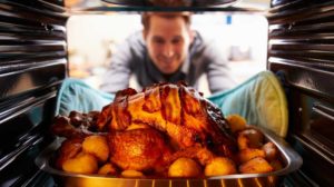 Man Taking Roast Turkey Out Of The Oven | 5 Ways to Avoid Gaining Weight Between Thanksgiving and New Year's Day | featured