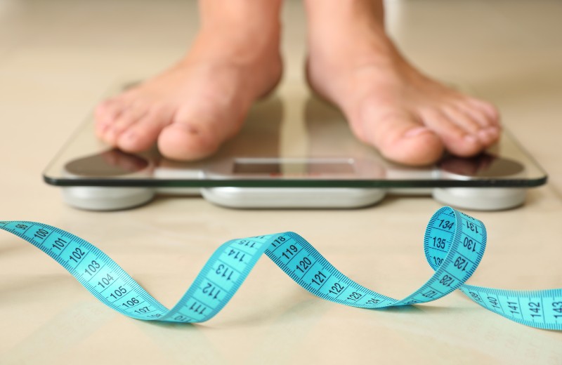 Tape in front of woman standing on floor scales indoors-Paleo Diet Myths