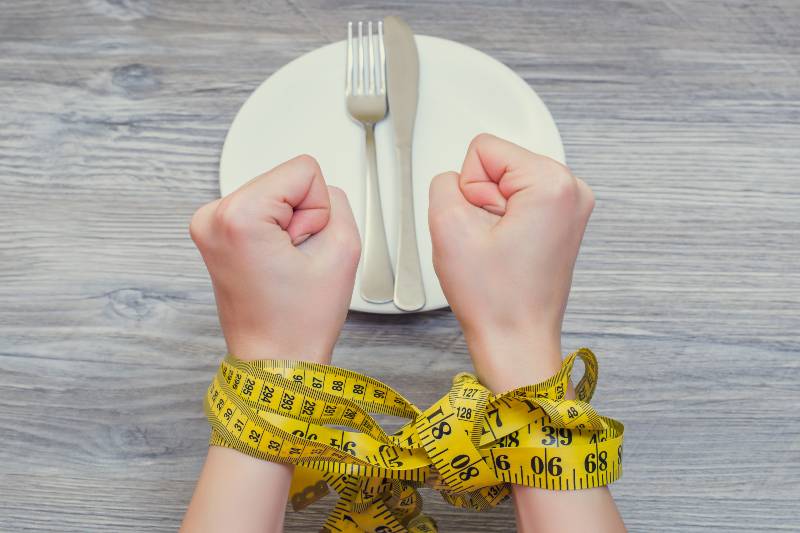 Woman's hands tied with tape measure-Paleo Diet Myths