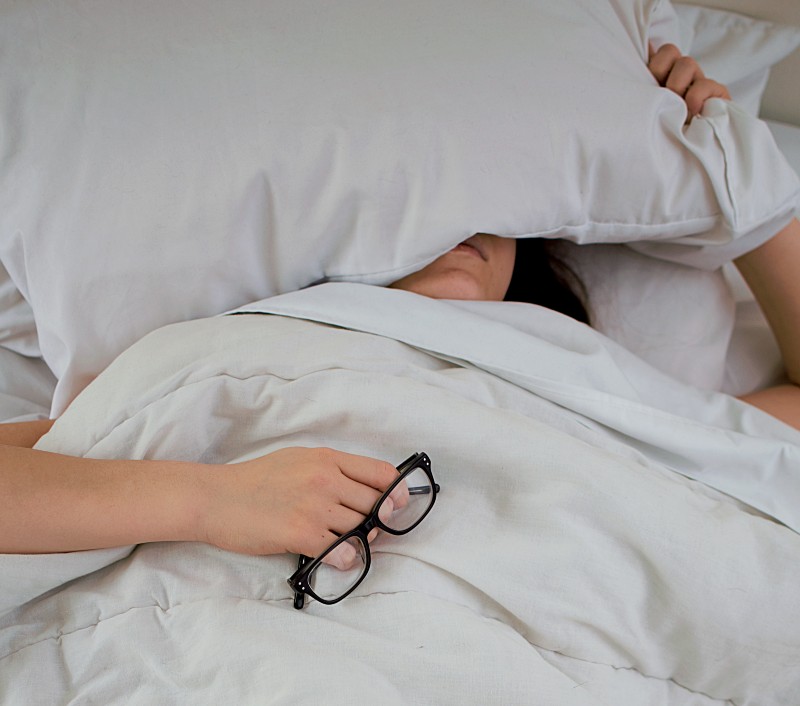 person lying on bed while covering face with pillow-Sleep Deprivation