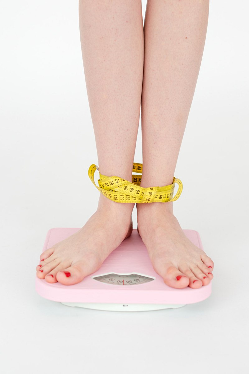 woman tied with measuring tape standing on scales | medical benefits of juicing 