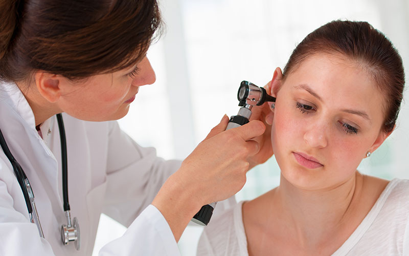 ENT physician looking into patient's ear with an instrument | Does Tinnitus Go Away | 9 Signs That Tinnitus is Going Away