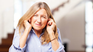senior beautiful woman covering ears | Does Tinnitus Go Away | 9 Signs That Tinnitus is Going Away | Featured