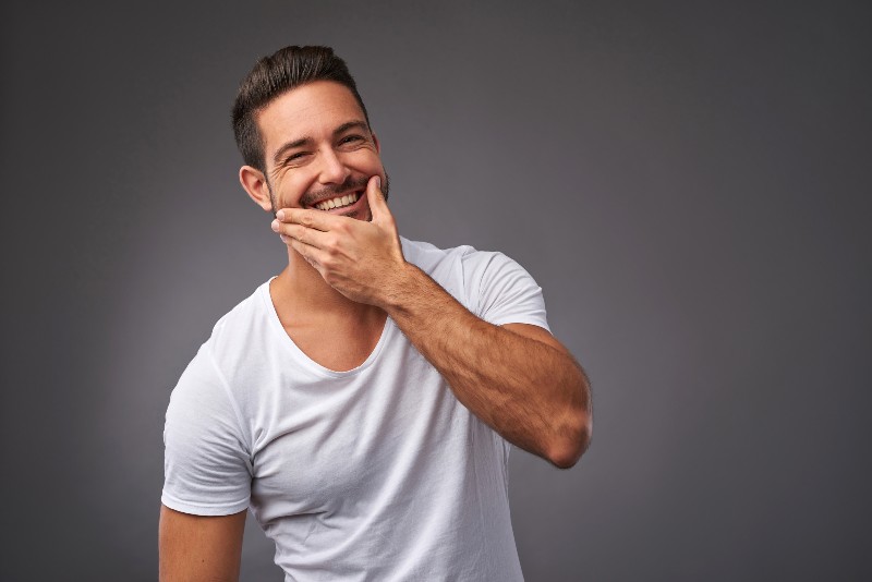 A handsome young man checking the skin on his face and smiling | curcumin benefits