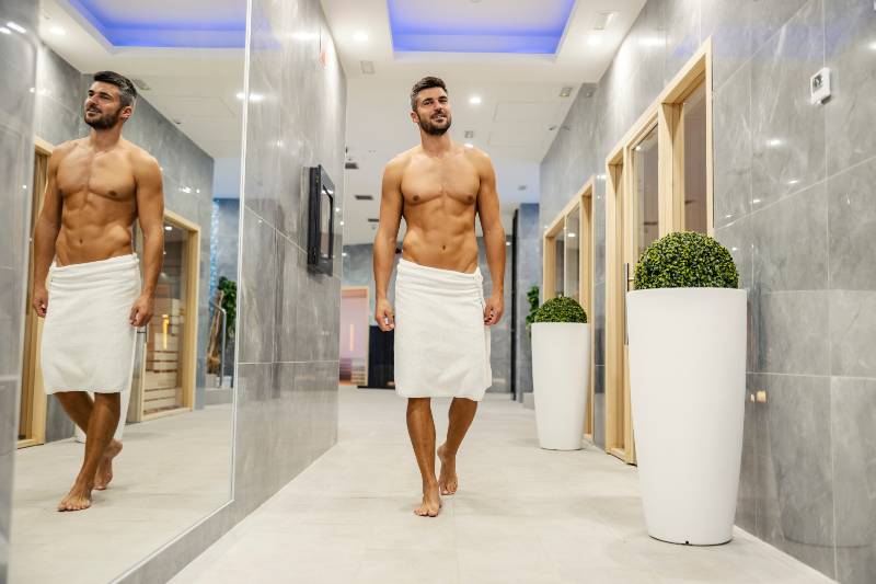 A handsome muscular macho man wrapped in a towel walking around the spa center | Beta-Glucan