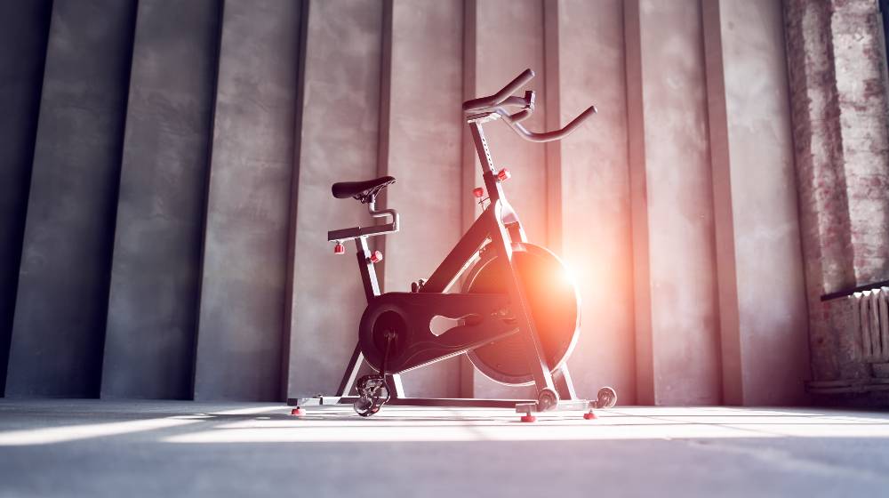 Bike on gray concrete wall in gym | Updated List of Best Exercise Bikes for Tall Person 2022 | featured